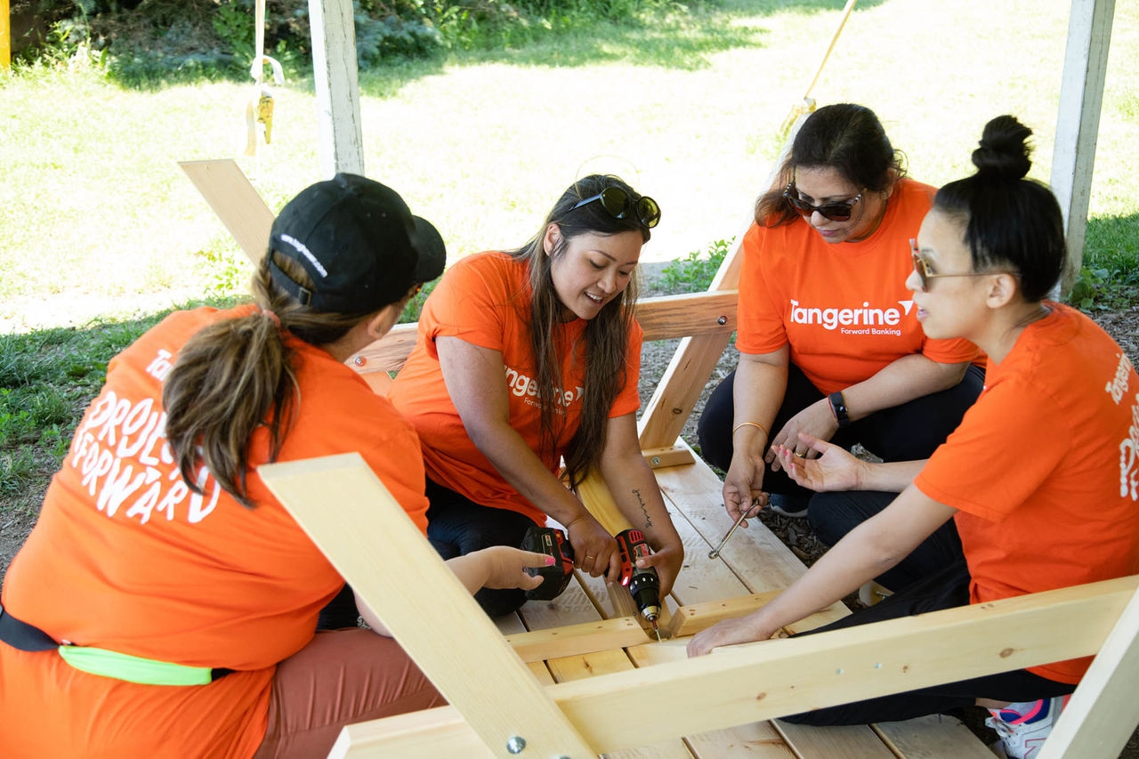 Quatre employés de Tangerine en train de bâtir une table de pique-nique