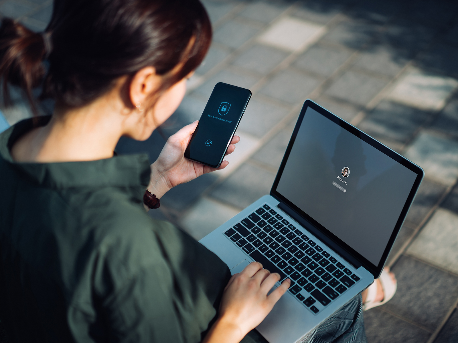 A woman using a multi-factor authentication mobile app on her phone to log into her laptop.