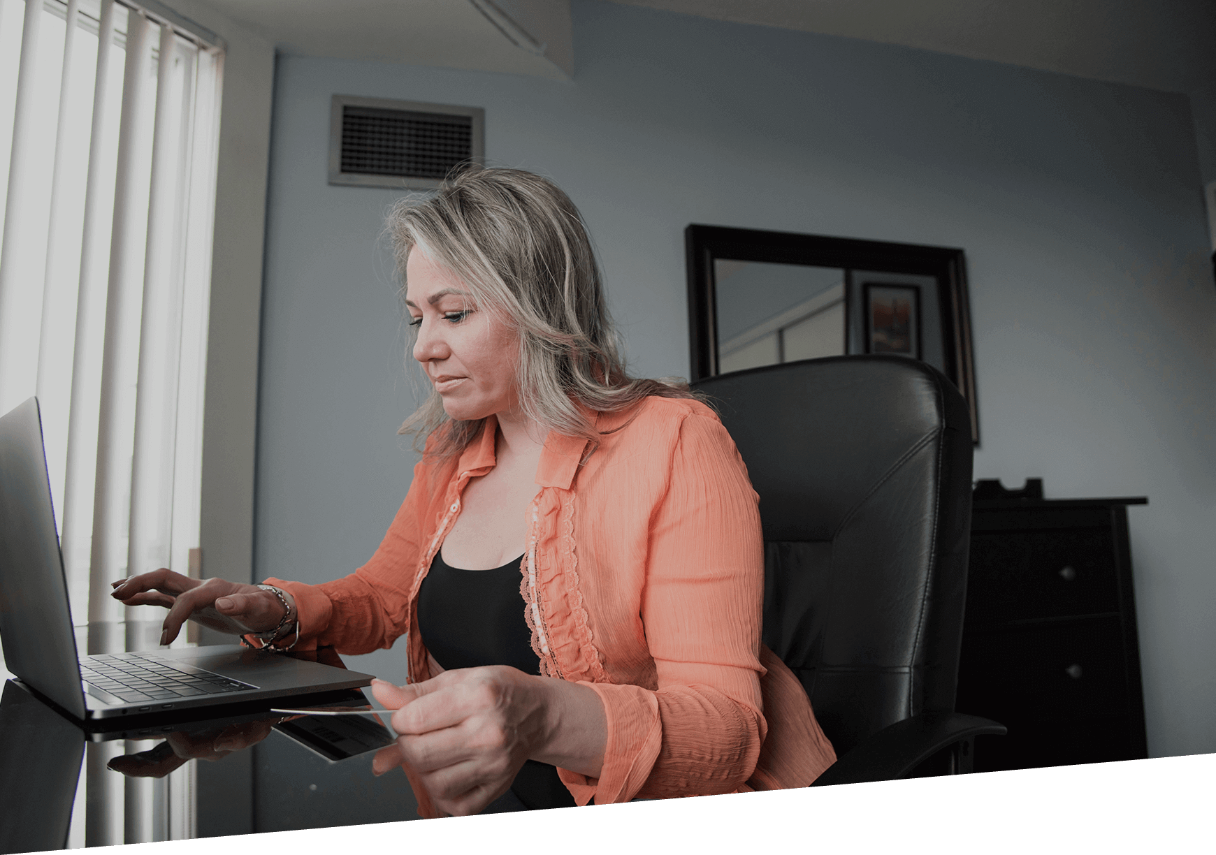 A lady entering payment details from a payment card on a PC.