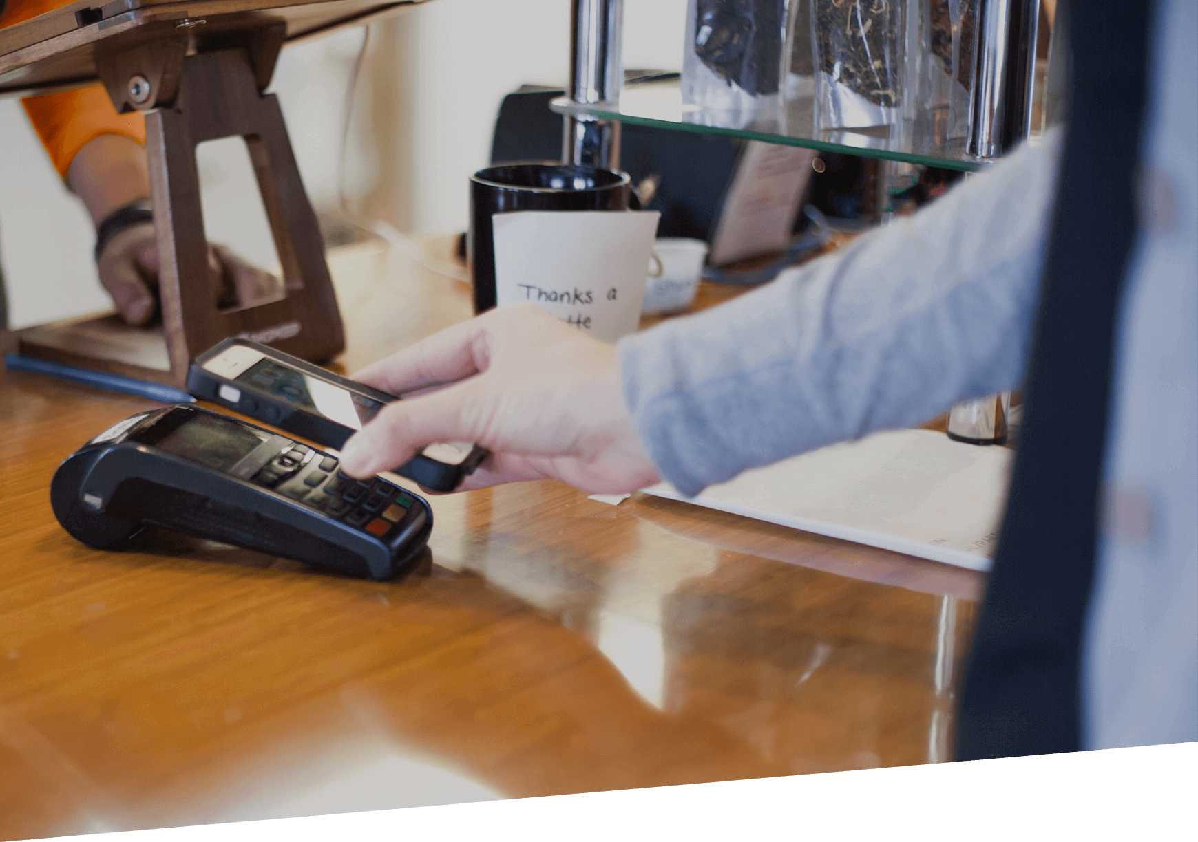 A person making a payment at a cashier using a mobile phone.