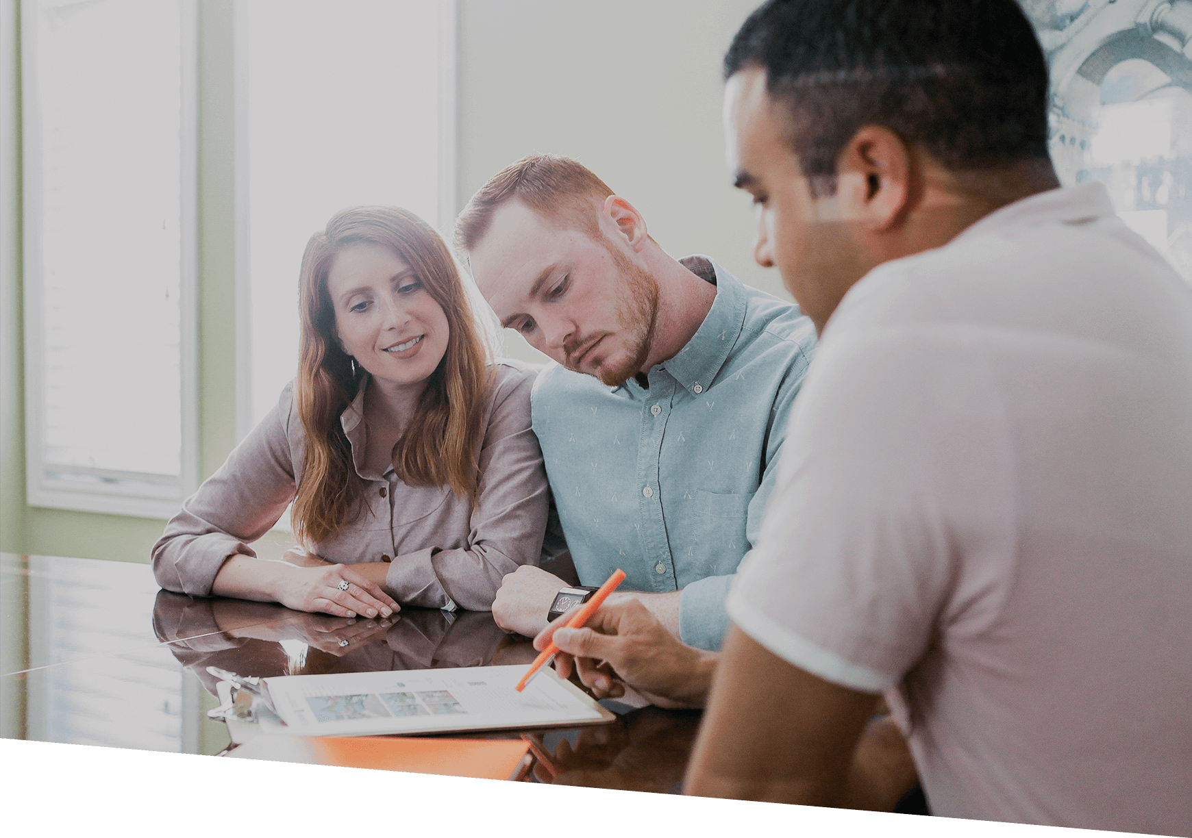 A person explaining details on a document to a couple.