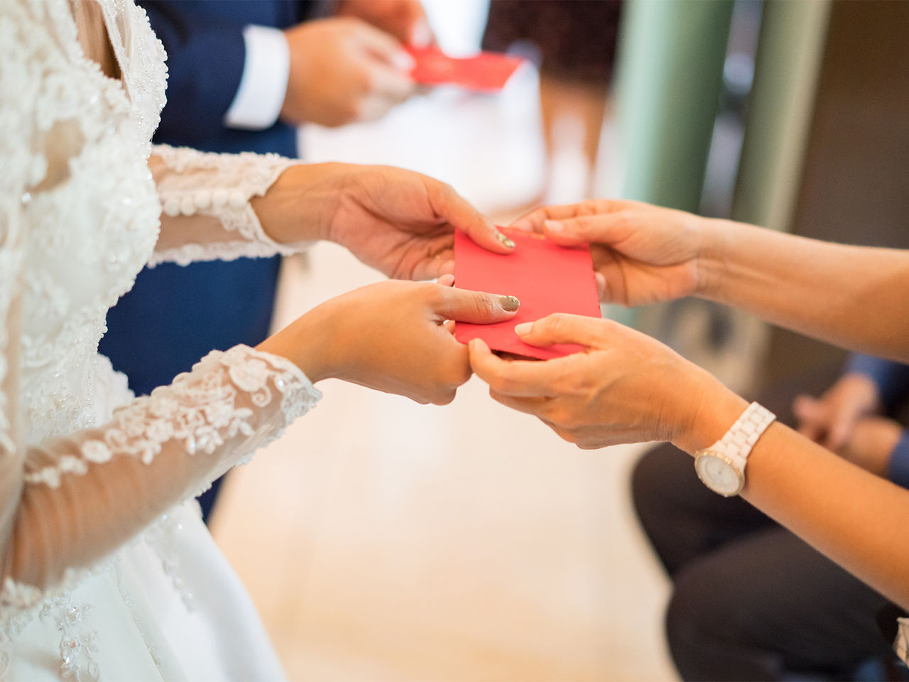 A bride and a groom accepting red envelops given by a guest.