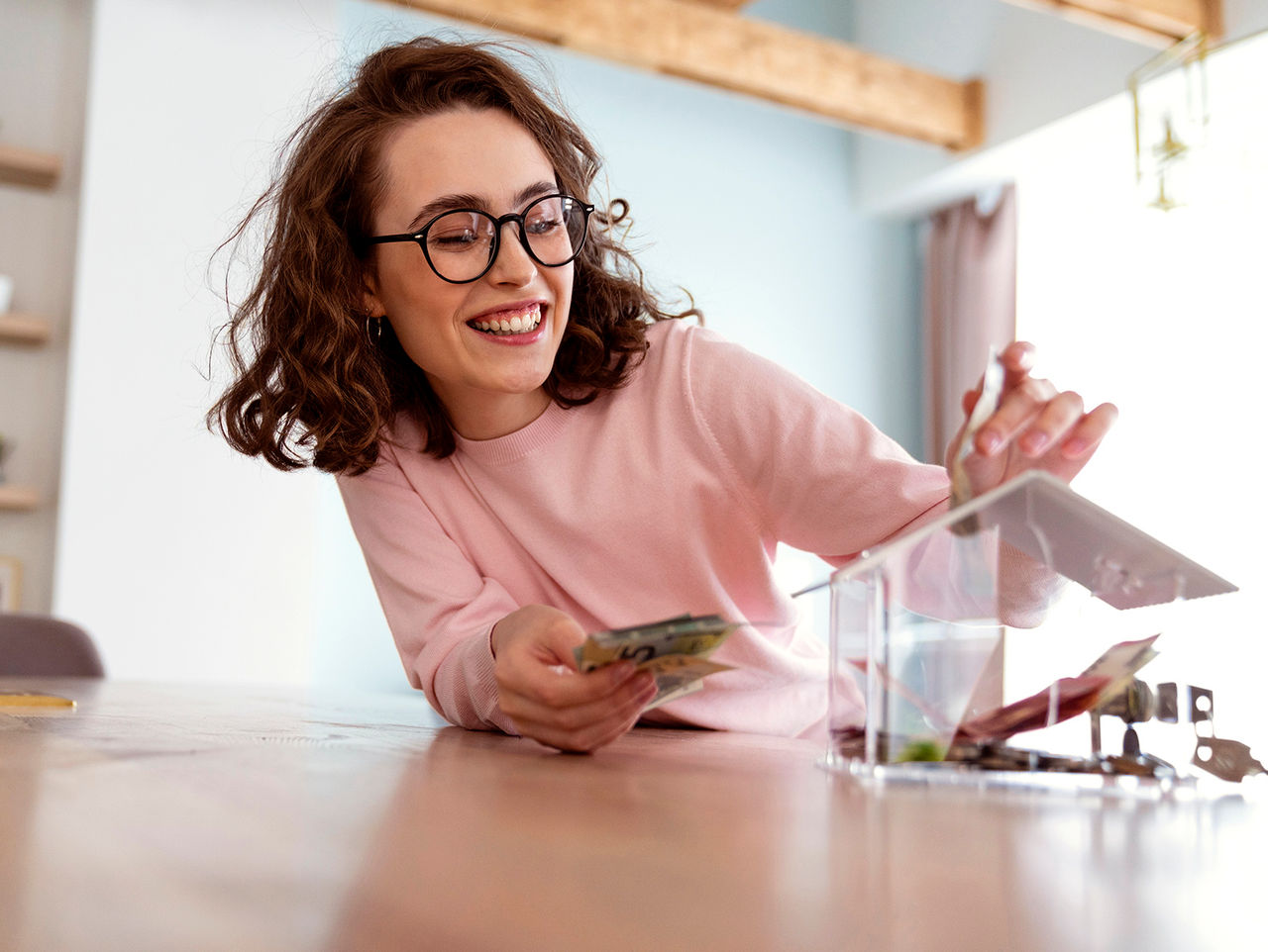 Happy woman saving money in piggy bank at home