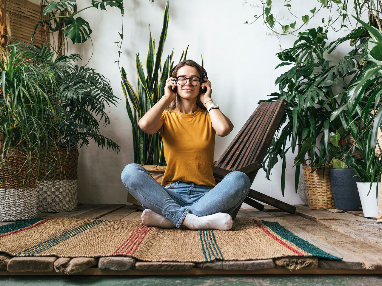 Relaxed young woman sitting on the floor at home listening to music