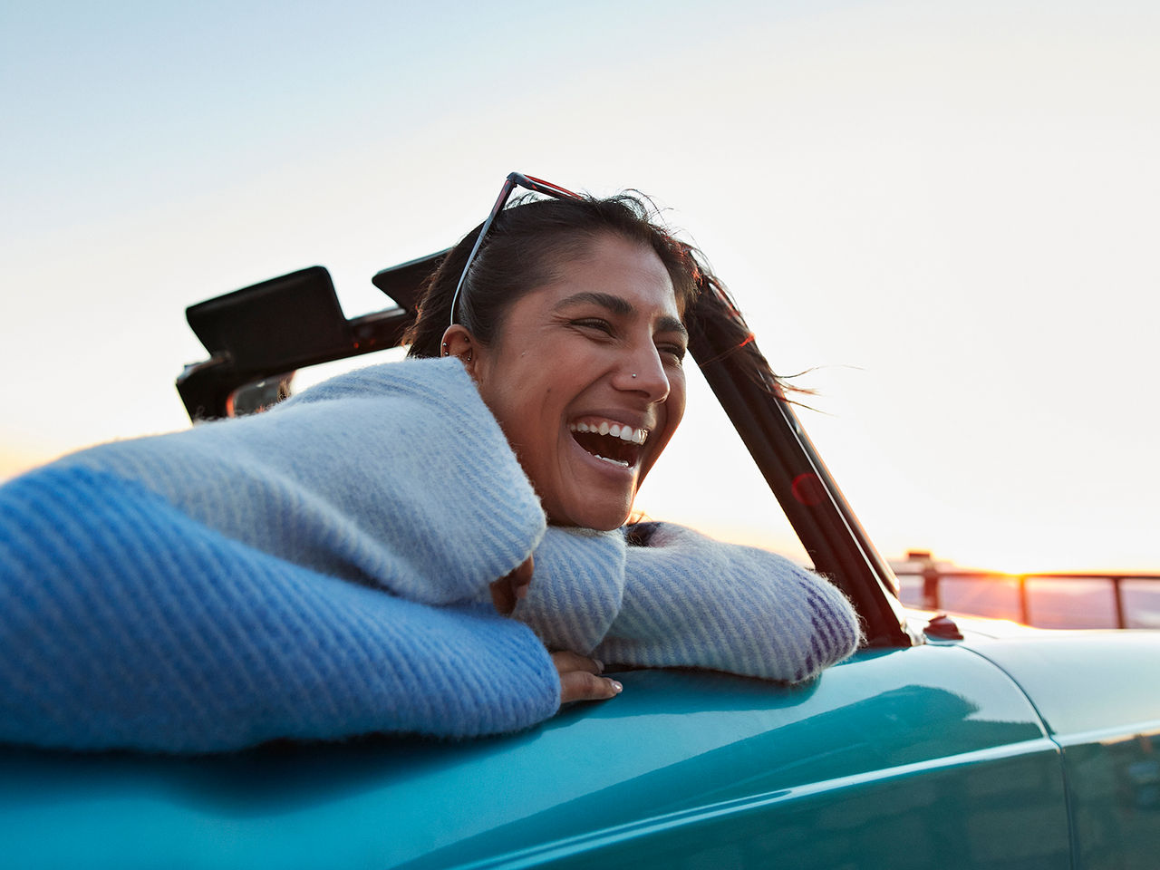 Une femme souriante dans une décapotable bleue